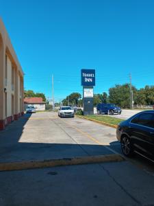 ein Schild für ein Hotel mit Autos auf einem Parkplatz in der Unterkunft Travel Inn Winter Haven in Winter Haven