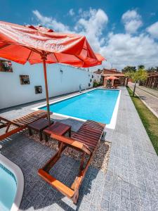 a pool with chairs and an umbrella next to a swimming pool at Pousada Vasto Horizonte in Barreirinhas