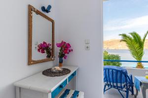 a mirror on a wall next to a table with flowers at Antoniadi Rooms in Livadia