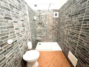 a bathroom with a toilet and a brick wall at Affittacamere Virginia's Rooms in Genoa