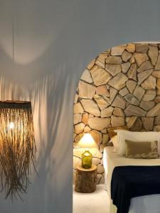 a bedroom with a stone wall and a bed and a lamp at Kûara Pipa in Pipa