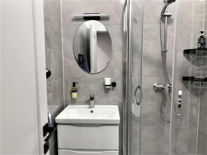 a bathroom with a sink and a shower with a mirror at Glorious Apartment Near The Old City in Lviv