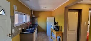 cocina con paredes amarillas, fregadero y nevera en El Gran Montañes, en Lago Puelo