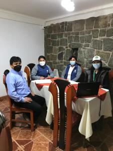 un groupe de personnes assises à une table portant des masques dans l'établissement Viandina Machupicchu, à Machu Picchu