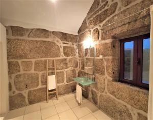 a stone walled bathroom with a sink and a window at Quinta da Adarnela in Lagares da Beira +40 photos