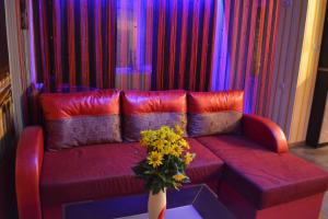 a red couch with a vase of flowers on a table at ApartLux Chernigov in Chernihiv