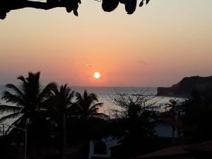 - un coucher de soleil sur l'océan avec des palmiers dans l'établissement Pousada Chalés do Castelo, à Icapuí