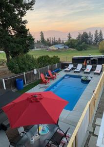 einen roten Sonnenschirm und Stühle sowie einen Pool in der Unterkunft Salish B&B and Spa in West Kelowna