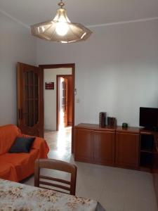 sala de estar con sofá naranja y TV en BRUNO TURIN APARTMENT Near the METRO, en Collegno