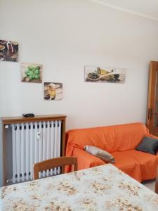 ein Wohnzimmer mit einem orangenen Sofa und einem Tisch in der Unterkunft BRUNO TURIN APARTMENT Near the METRO in Collegno