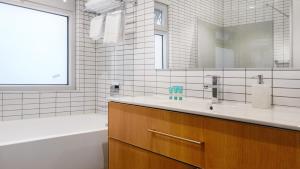 y baño con lavabo, bañera y espejo. en Semaphore Splash Apartments en Port Adelaide