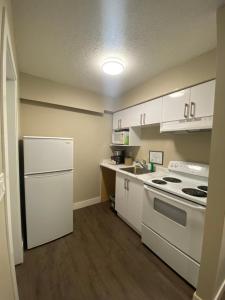 a small kitchen with white cabinets and a stove at Imperial Motel in One Hundred Mile House