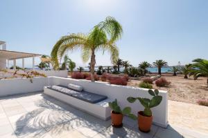 a patio with a bench and palm trees and the ocean at The view 2 in Kampos Paros