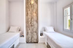 two beds in a room with white walls and a window at The view 2 in Kampos Paros