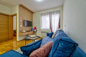 a living room with a blue couch and a television at Apartman Sanjalica in Zlatibor