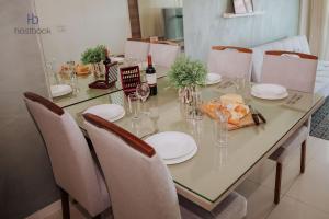 a dining room table with white plates and wine bottles at Apto espetacular no Pecado entre MAR e LAGOA - WIFI 200MB - Piscina com vista - Garagem - 2 Quartos - TV Smart - Cozinha equipada - Churrasqueira - Ar condicionado in Macaé