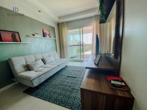 a living room with a couch and a tv at Apto espetacular no Pecado entre MAR e LAGOA - WIFI 200MB - Piscina com vista - Garagem - 2 Quartos - TV Smart - Cozinha equipada - Churrasqueira - Ar condicionado in Macaé