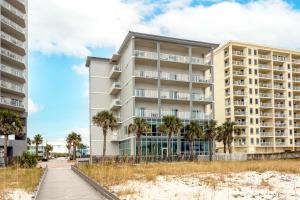 a building on the beach with palm trees and a boardwalk at Seawind #1109 in Gulf Shores