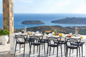 a dining table with chairs and a view of the ocean at Elounda Villa Kalydon in Elounda
