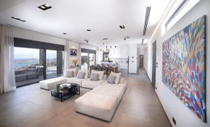 una sala de estar con muebles blancos y una gran pintura en Elounda Villa Kalydon en Elounda
