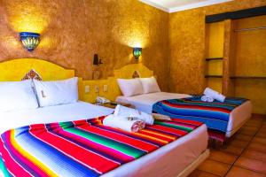 a bedroom with two beds with colorful sheets at Hacienda Maria Bonita Hotel in Playa del Carmen