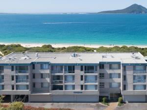 an apartment building with the beach in the background at Ocean Shores 12 Waterfront Unit with Sensational Water Views WiFI and Air Conditioning in Nelson Bay