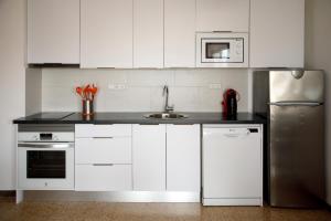 uma cozinha com armários brancos e um frigorífico de aço inoxidável em Apartamento Bahia III em Empuriabrava