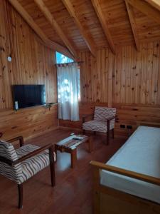 Cabaña de madera con mesa, sillas y TV en Departamentos Sonne Depto Planta Alta en San Martín de los Andes