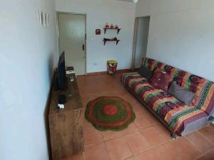 ein Wohnzimmer mit einem Sofa und einem TV in der Unterkunft Apartamento inteiro em Peruíbe no centro, próx a praia in Peruíbe