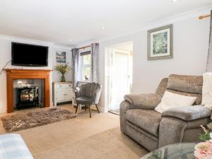 a living room with a couch and a fireplace at Cosy Cottage in Sidley