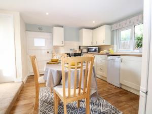 a kitchen with a table and chairs in a kitchen at Cosy Cottage in Sidley
