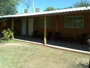 a house with chairs and tables in front of it at LUMALU Deptos in Villa Cura Brochero