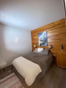 a bedroom with a bed and a wooden wall at Appartement lumineux aux pieds des pistes in Saint-François-Longchamp