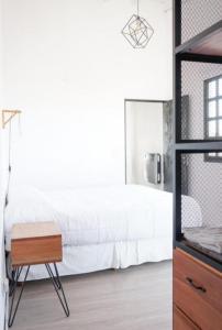 Schlafzimmer mit einem weißen Bett und einem Holztisch in der Unterkunft Casa y departamento con pileta Aeropuerto Circunvalacion Kempes Quorum -cambio oficial- in Cordoba