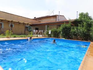 two people swimming in a large blue swimming pool at Las Lucías, experiencias de ecoturismo in Navatrasierra