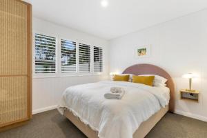 a white bedroom with a large bed with yellow pillows at Sunset Beach in Brunswick Heads