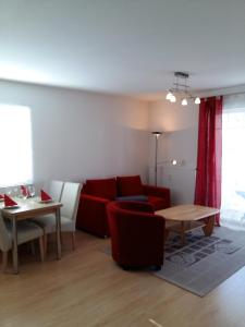uma sala de estar com um sofá vermelho e uma mesa em Ferienwohnung H 11 em Graal-Müritz