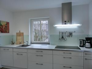 eine weiße Küche mit einem Waschbecken und einem Fenster in der Unterkunft Ferienwohnung LFR21 in Graal-Müritz