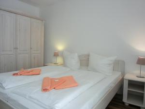 - un lit blanc avec 2 serviettes orange dans l'établissement Ferienwohnung W18 2 N, à Graal-Müritz