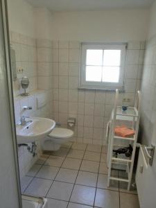 Baño blanco con lavabo y aseo en Ferienwohnung U3 "Godewind", en Graal-Müritz