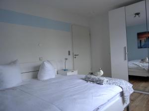 um quarto branco com uma cama grande e um espelho em Ferienwohnung LP7 "Seestern" em Graal-Müritz