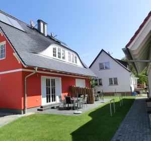 a red and white house with chairs and tables at Ferienhaus FH T 1d in Graal-Müritz