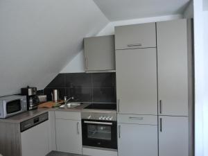 a kitchen with white cabinets and a stove top oven at Ferienwohnung P15 in Graal-Müritz
