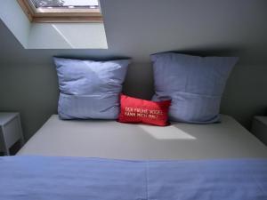 a bed with two pillows and a red pillow at Ferienwohnung P15 in Graal-Müritz