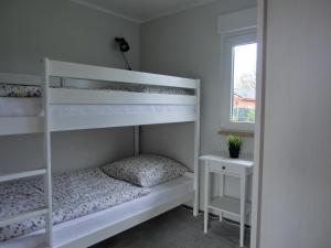 a bedroom with white bunk beds and a window at Ferienhaus FH20 in Graal-Müritz