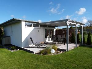 a white house with a pergola in the yard at Ferienhaus FH20 in Graal-Müritz