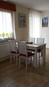 een eetkamer met een tafel, stoelen en ramen bij Ferienwohnung S33 "Leuchtturm" in Graal-Müritz