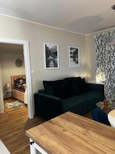 a living room with a black couch and a bed at Apartament Sadowa 87 in Elblag