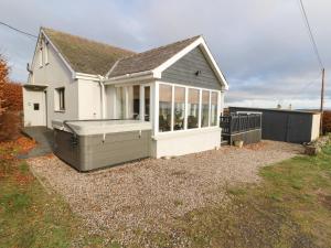 een klein wit huis met een hot tub in de tuin bij West Cottage in Forfar