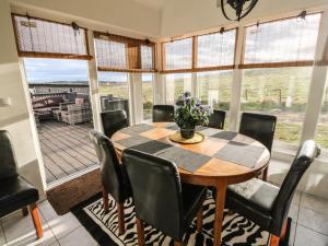 een eetkamer met een tafel, stoelen en ramen bij West Cottage in Forfar